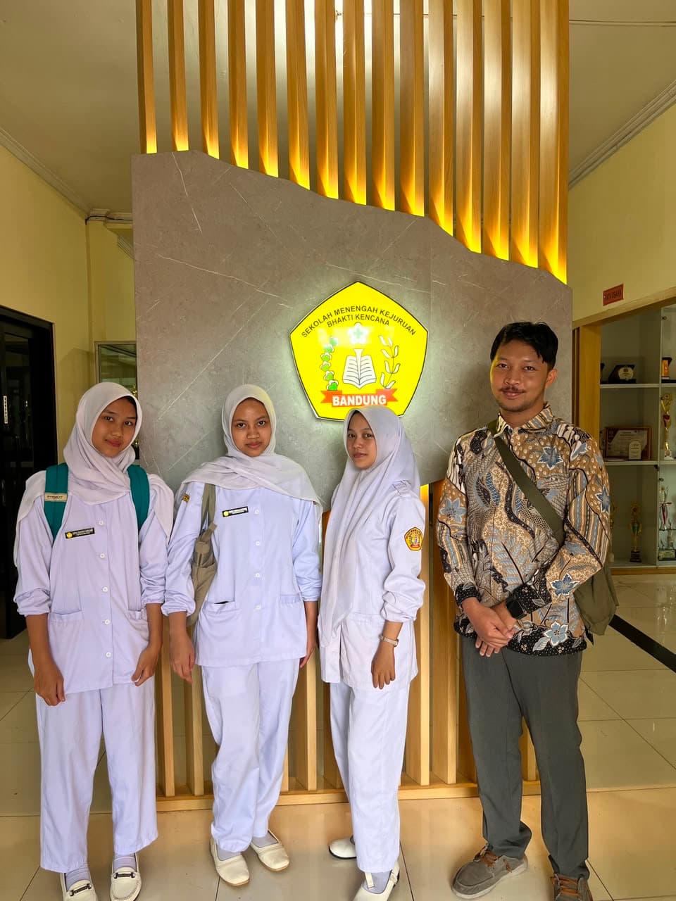 A team member with three trainee caregivers in uniform at a vocational nursing school in Bandung