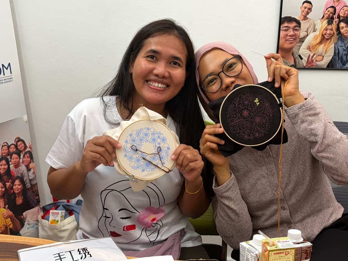 Two helpers smiling with their finished embroidery