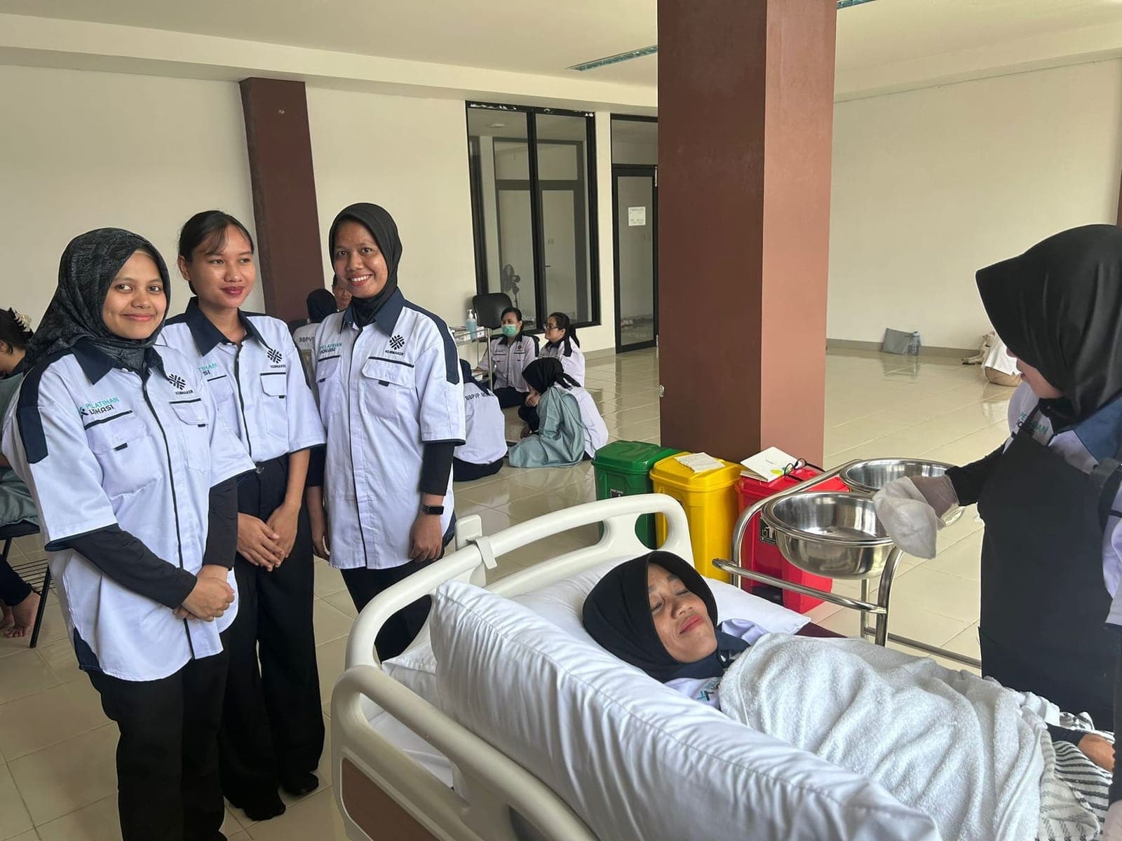Caregivers in training uniform beside a practice bed at BBPVP Bekasi