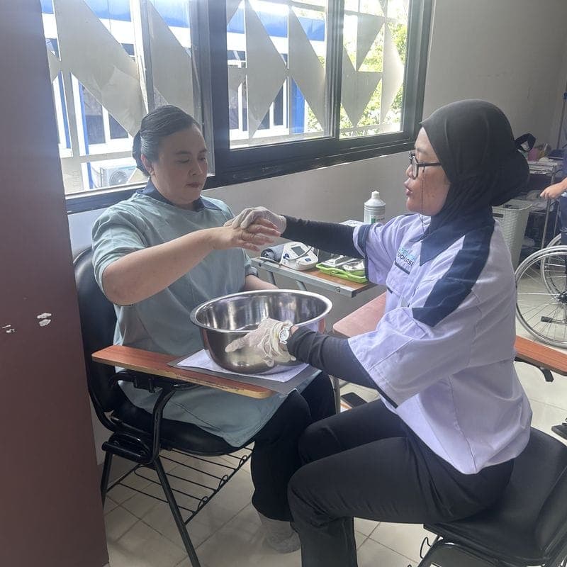 A trainee caregiver helping a person wash their hands
