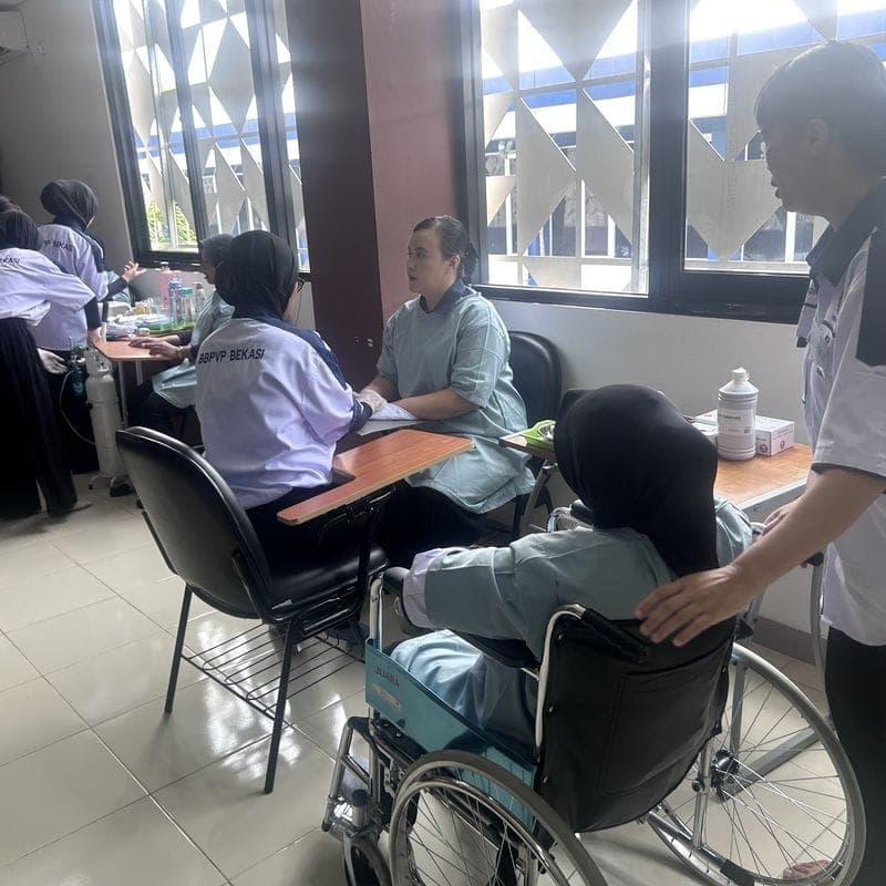 A trainee caregiver helping a person in a wheelchair