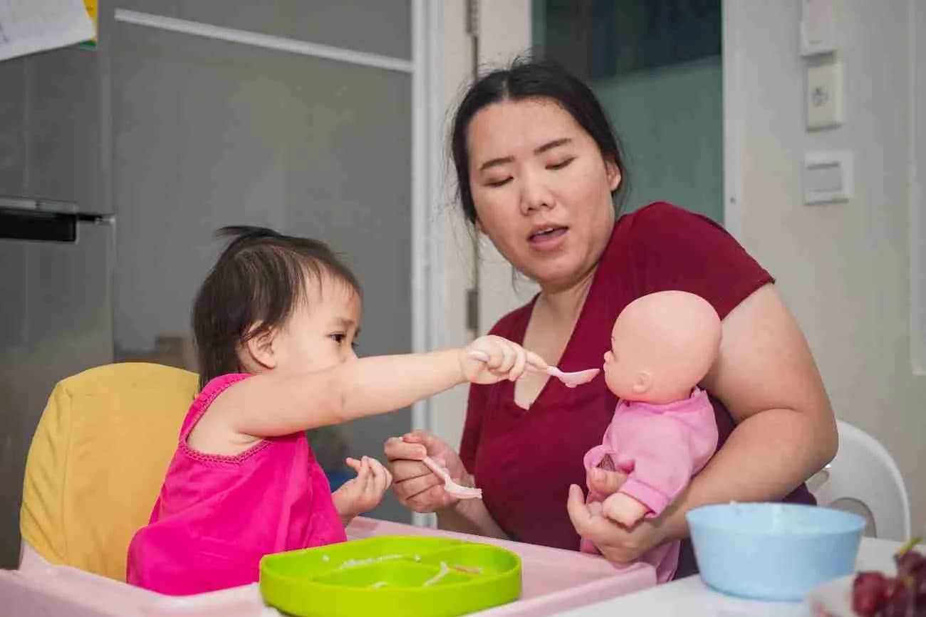 A helper entertaining a toddler at mealtime