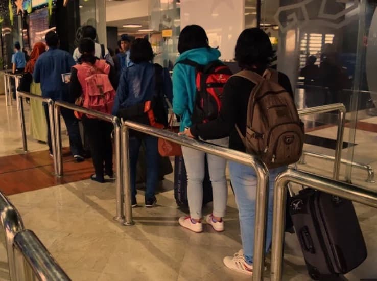 Helpers queuing at the airport, seen from behind