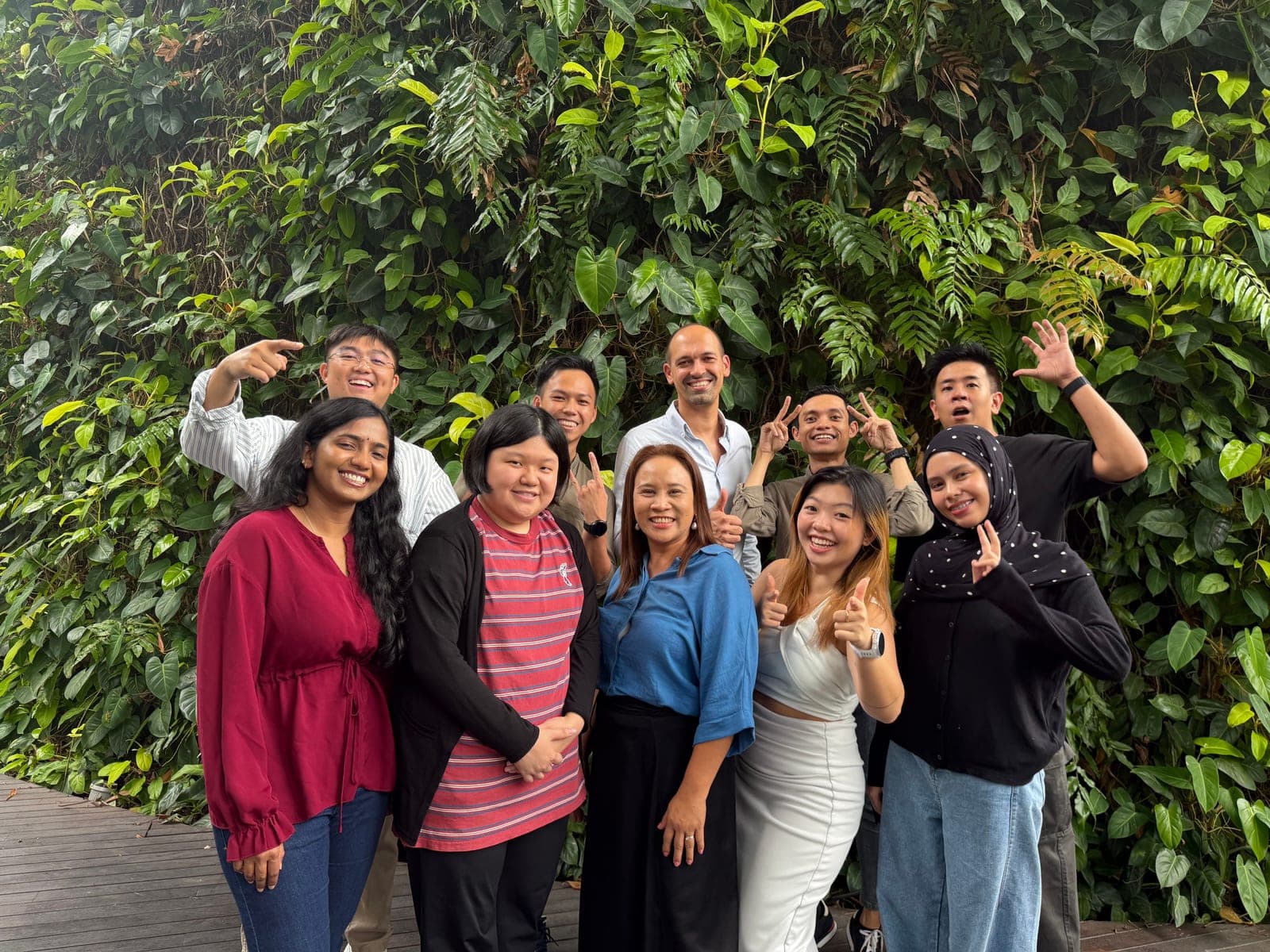 The We Are Caring team together in front of a green wall